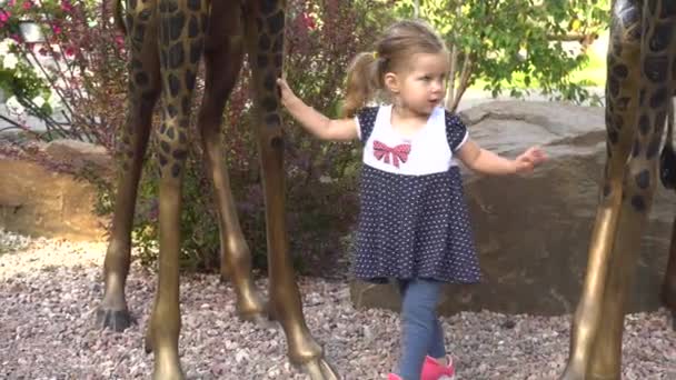 Cute girl near giraffe statues — Stock Video