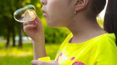 Küçük kız parkta sabun köpüğü üfleme. Closeup video