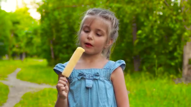 Girl eating popsicle ice-cream in park — Stock Video