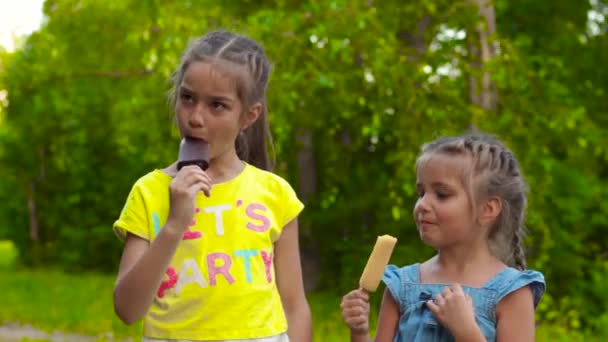 Dwie dziewczyny jedzenie lodów popsicle w parku — Wideo stockowe