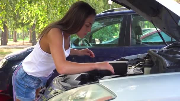 Mujer tratando de arreglar el coche por sí misma — Vídeo de stock