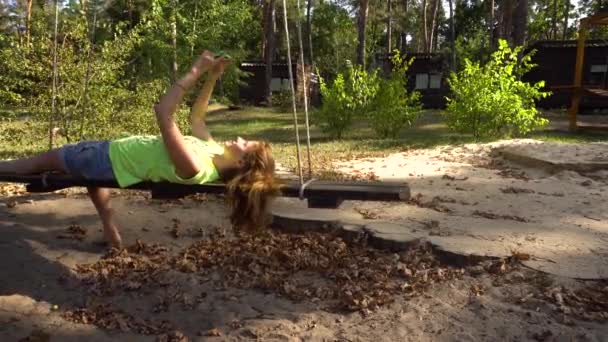 Woman on swings with smartphone making selfy — Stock Video
