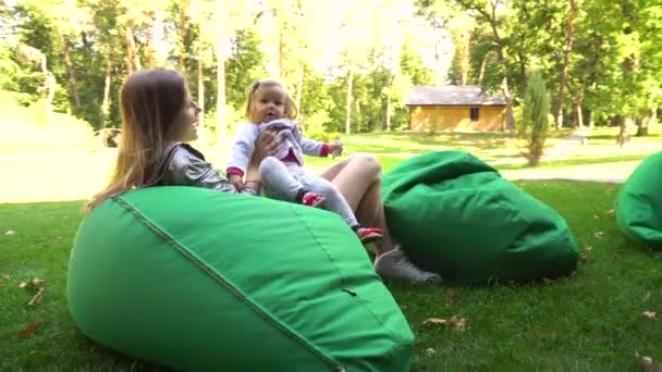 Moeder van de vrouw en meisje dochter plezier op zitzakken in de natuur — Stockvideo