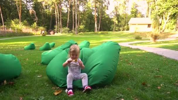 Petite fille s'amuser sur des sacs de fèves dans la nature — Video