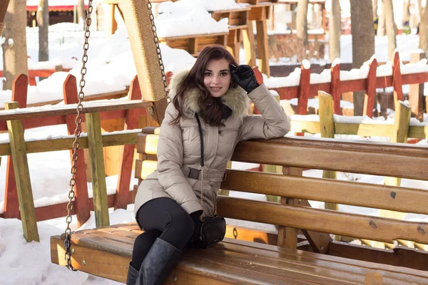 Giovane donna nel parco invernale seduta sulla panchina — Foto Stock