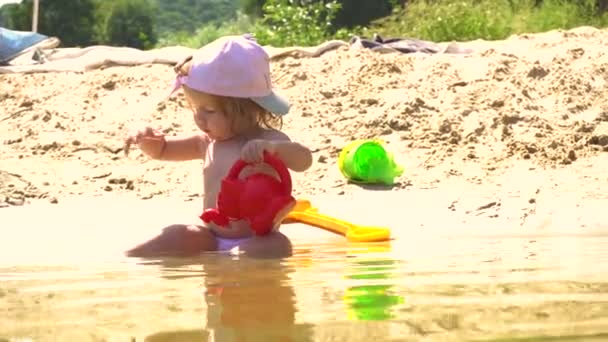 Cute girl on beach playing with watering pot — Stock Video