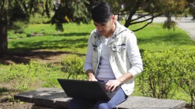 Parkta dizüstü bilgisayarı olan adam.