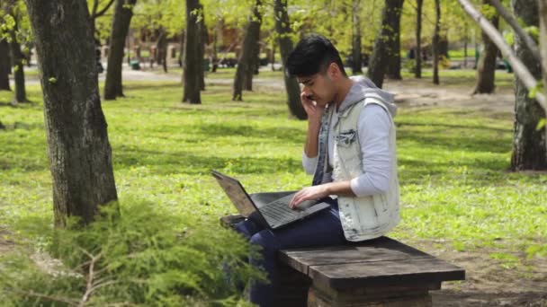 Uomo con computer portatile nel parco che parla al telefono in estate — Video Stock