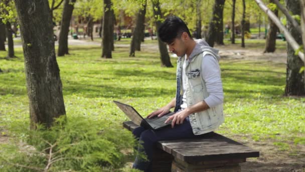 Man freelancer working on black laptop in the park — Stock Video