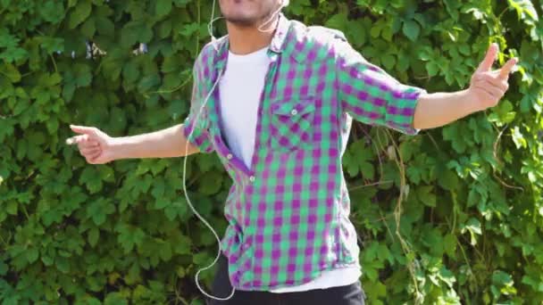 Asian young man in earphones dancing in park — Stock Video