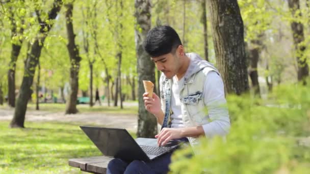 Asiatique homme pigiste travailler sur ordinateur portable et manger de la crème glacée — Video