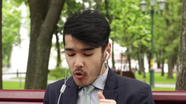 公園で座っているとフレンチ フライを食べるアジア人実業家 — ストック動画