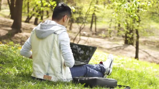 Mosolygó etnikai ember használ laptop Park — Stock videók