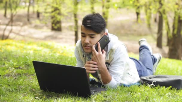 Człowiek pracuje na laptopie i rozmawia przez telefon — Wideo stockowe