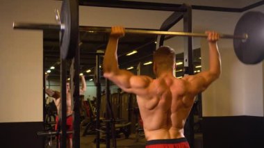 Arkadan görünüşü kas adam modern spor salonunda ayna yakın dururken ağır halter kaldırma