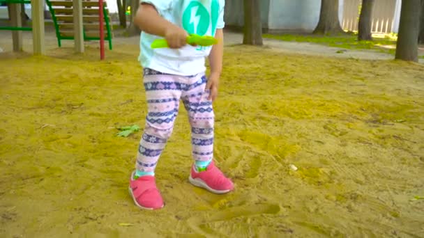 Chica con la pala caminando y jugando con la arena — Vídeos de Stock