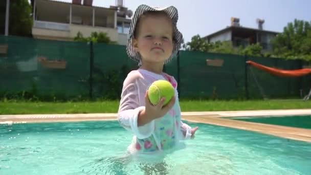 Girl playing with tennis ball in swimming pool