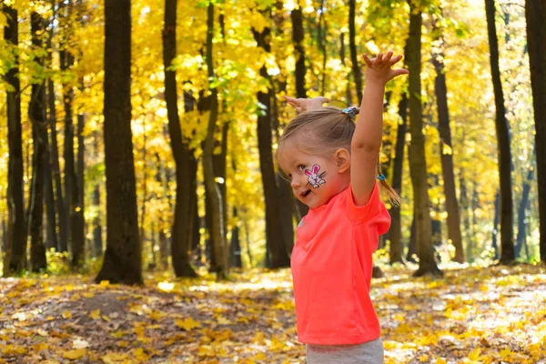 Маленькая счастливая девочка играет в осеннем парке — стоковое фото