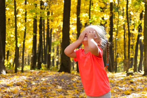 Девушка играет в прятки в осеннем парке — стоковое фото