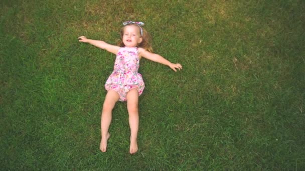 Kleines Mädchen legt sich auf Rasen — Stockvideo