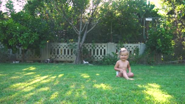 Маленька дівчинка стрибає і падає на газон — стокове відео