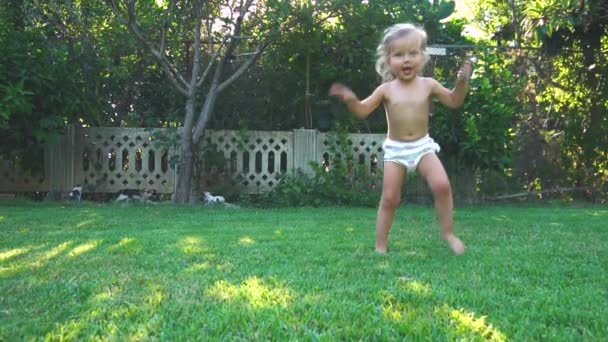 Kleines lächelndes Mädchen springt in Zeitlupe auf Rasen — Stockvideo