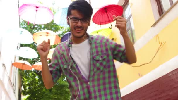 Happy man is dancing under colorful umbrellas — Stock Video