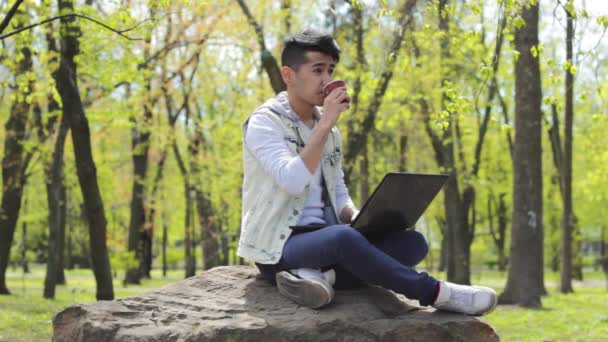 Азиатский фрилансер работает на ноутбуке и пьет кофе — стоковое видео