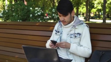 Smartphone ile konuşmak ve parkta oturan dizüstü bilgisayarda çalışan adam serbest meslek