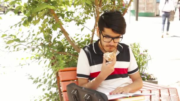 Estudiante aprendiendo y comiendo pasteles — Vídeos de Stock