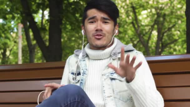 Hombre estudiante escuchando música en el parque — Vídeo de stock