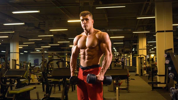 Hombre culturista posando de pie en el gimnasio grande —  Fotos de Stock