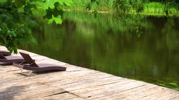 Chaises longues sur la jetée en bois sur la rivière sans personnes 