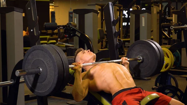 Uomo forte che fa esercizi con bilanciere in palestra — Foto Stock