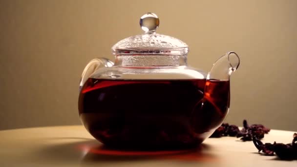 Théière filante avec thé hibiscus rouge sur la table 