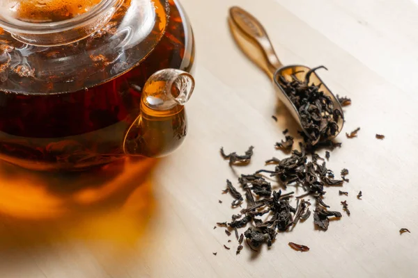 Closeup view on black tea leafs and teapot — Stock Photo, Image