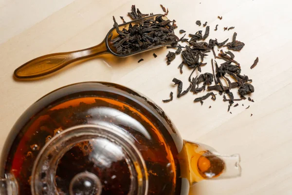 A lot of black indian tea leafs and teapot — Stock Photo, Image