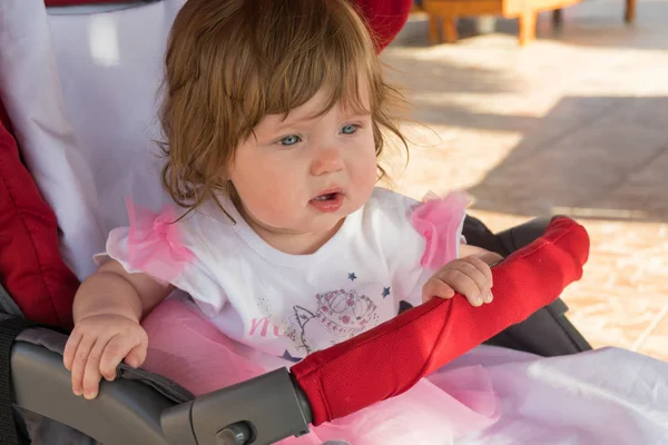 Kleine schattige babymeisje zit in de wandelwagen — Stockfoto