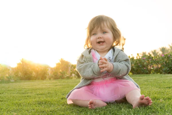 Pequena menina engraçada sentada na grama — Fotografia de Stock