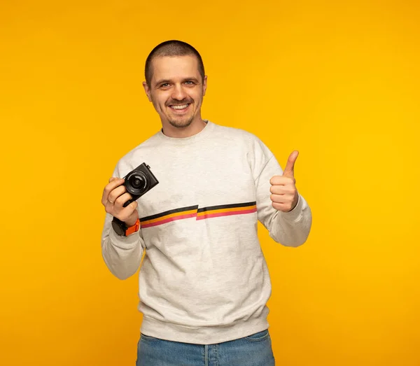 Чоловік фотограф або блогер тримає камеру і показує великі пальці вгору — стокове фото