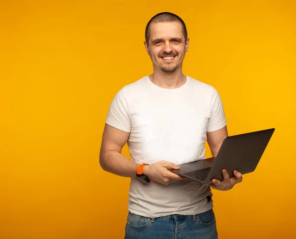 Homem freelancer em camisa branca segurando laptop e sorrindo — Fotografia de Stock