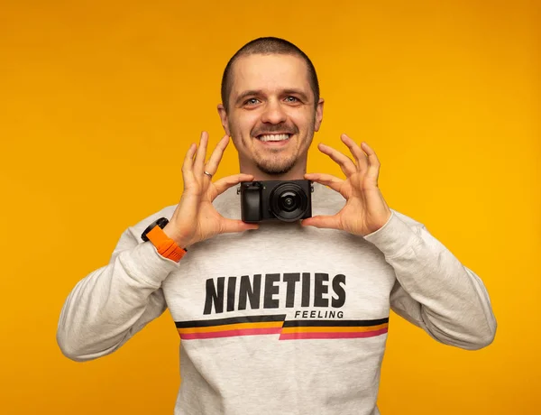 Homme photographe tenant caméra comme noeud papillon et souriant — Photo