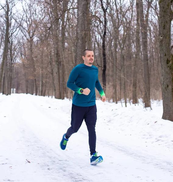 Hombre en ropa deportiva azul corriendo en el bosque —  Fotos de Stock