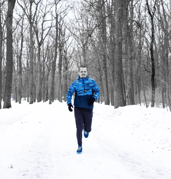 Hombre corredor corriendo en el bosque de invierno con chaqueta azul —  Fotos de Stock
