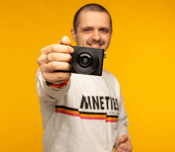 Mannen fotografen innehar mirorless kamera i hand och ler — Stockfoto