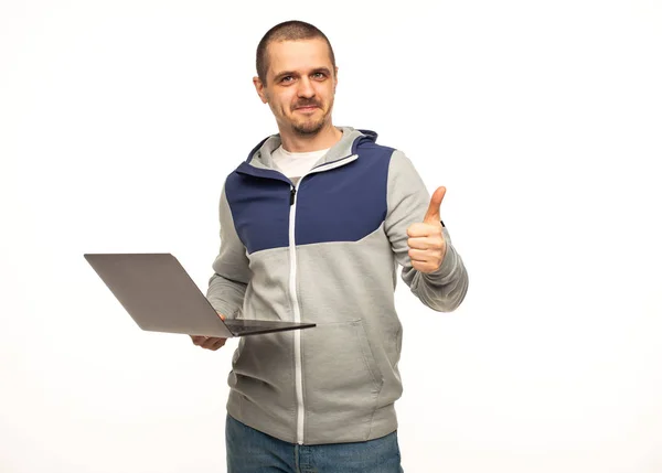 Чоловік фрілансер показує великі пальці вгору і тримає ноутбук в руках — стокове фото