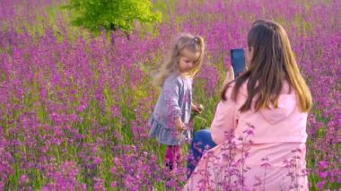 Tarlada kızının fotoğrafını çeken bir kadın.