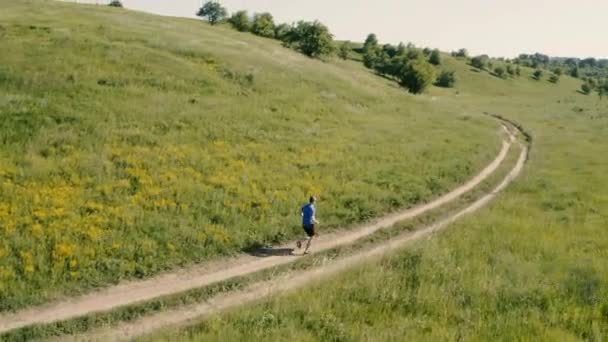 Adult man running outdoor on rural road. Aerial drone view. — Stockvideo