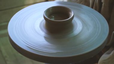 Çömlek heykeltraşı atölyede küçük bardak ya da tabak yapıyor.