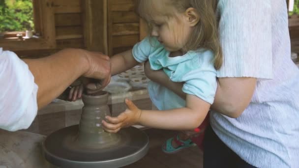 Ремесленник помогает девочке с изготовлением чашки на керамике — стоковое видео